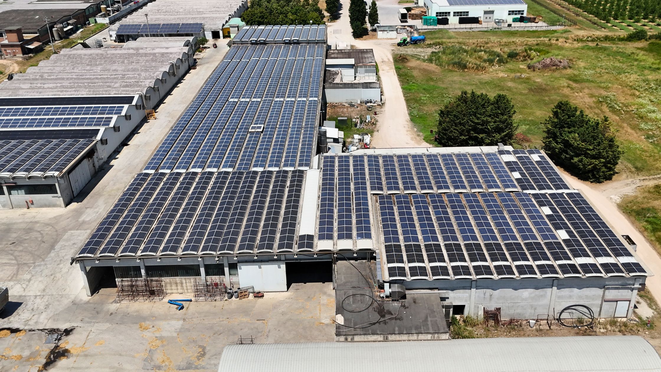 Impianto fotovoltaico industriale con pannelli solari installati sui tetti di capannoni agricoli e produttivi